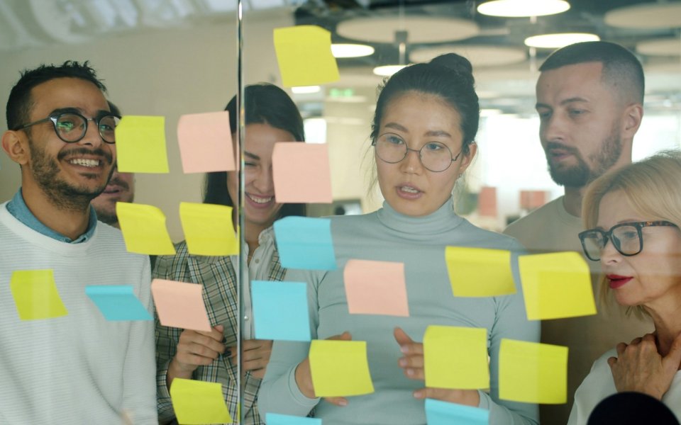 groep mensen staat samen te brainstormen met post its