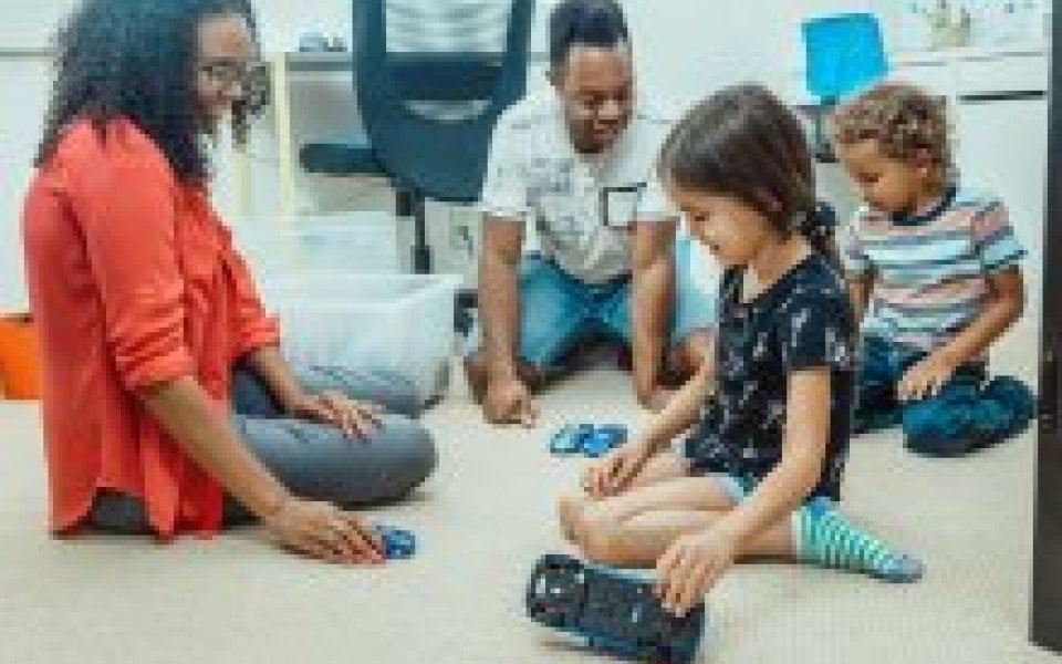 mama en papa spelen met hun zoontje en dochtertje op de grond