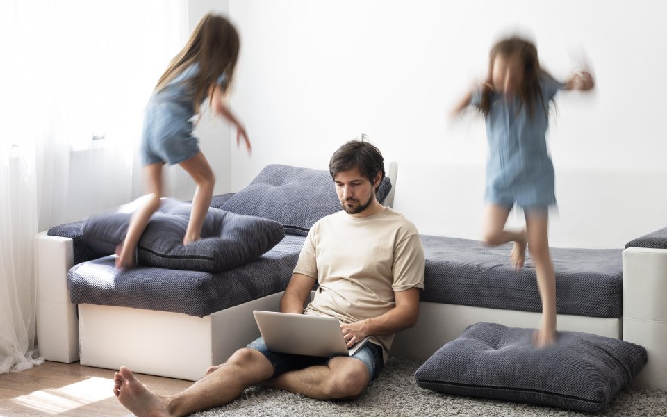 vader thuiswerkend terwijl kinderen op zetel springen