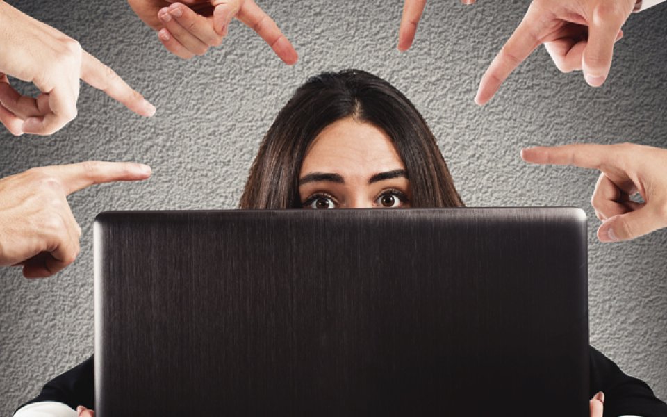 meerdere vingers wijzen beschuldigend naar vrouw achter laptop