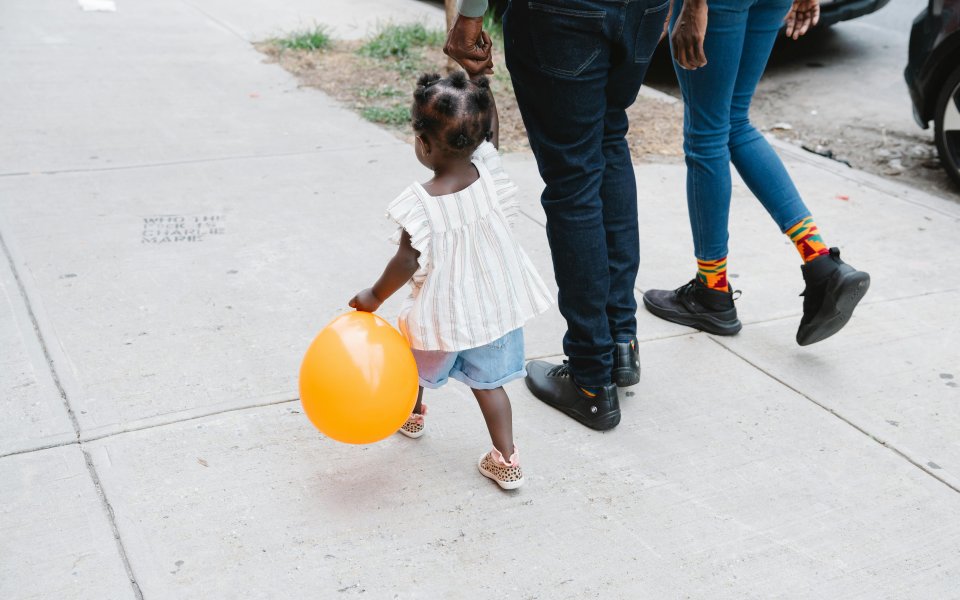 meisje-met-ballon--op-de-rug-gezien--wandelend-aan-de-hand-van-volwassene