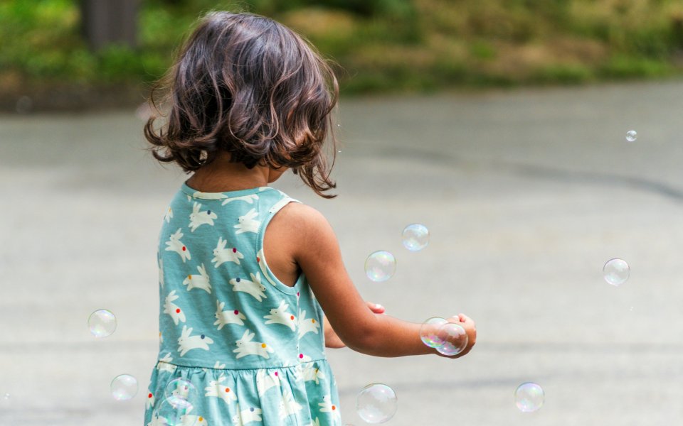 meisje-vangt-zeepbellen-op-een-speelplaats