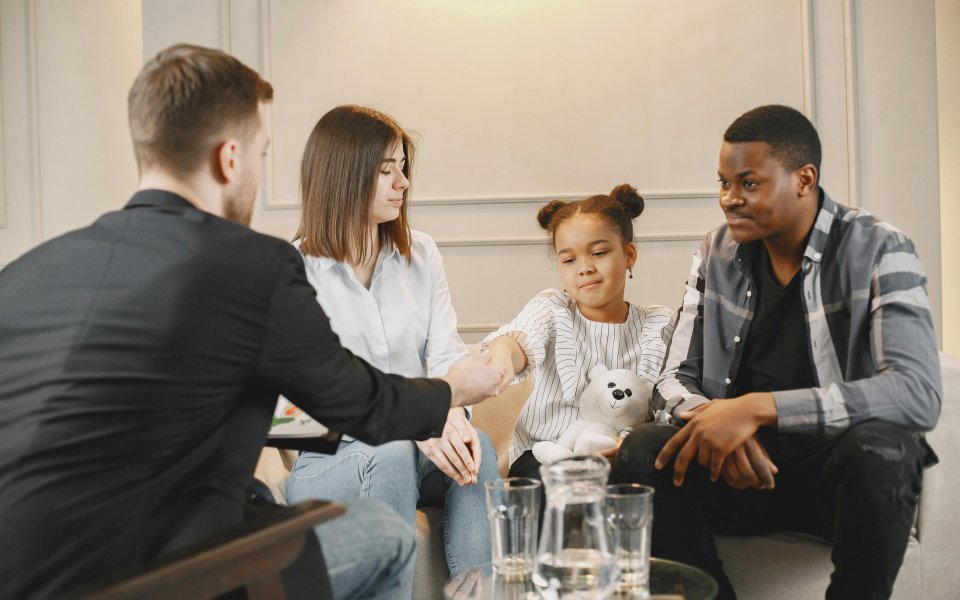 meisje-zit-tussen-haar-ouders-aan-tafel-bij-bemiddelaar-en-geeft-bemiddelaar-een-vuistje
