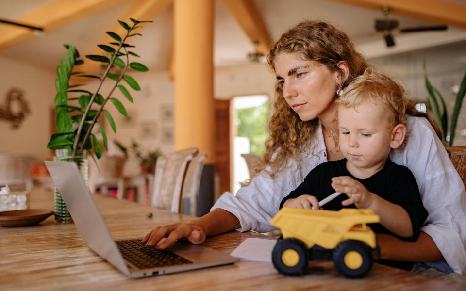 moeder--aan-computer-werkend--met-peuter-op-schoot