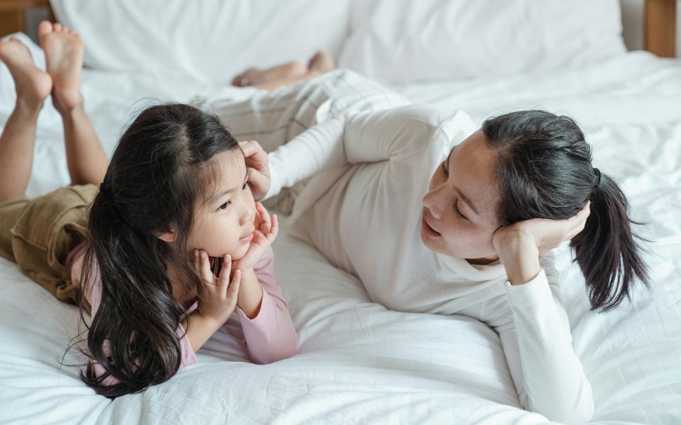 moeder-in-gesprekje-met-dochtertje--liggend-op-bed