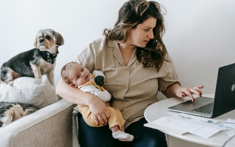 moeder-zit-te-werken-op-latop-met-baby-in-armen