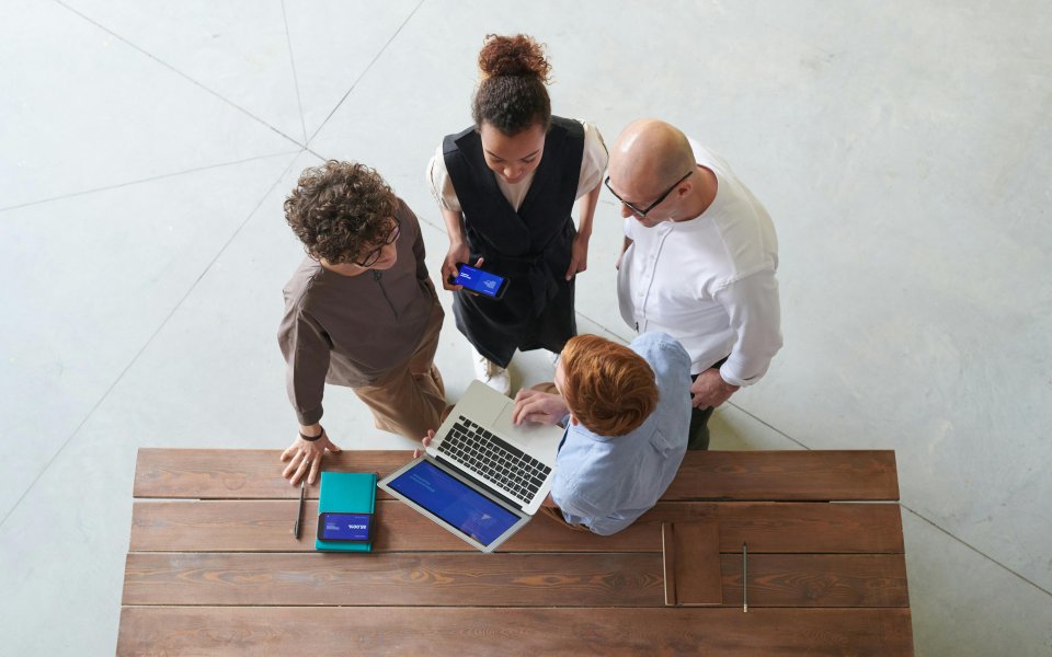 Professionelen die rond een laptop samenwerken