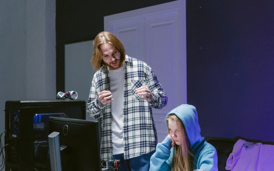 ouder-praat-tegen-meisje--dat-achter-computerschermen-zit