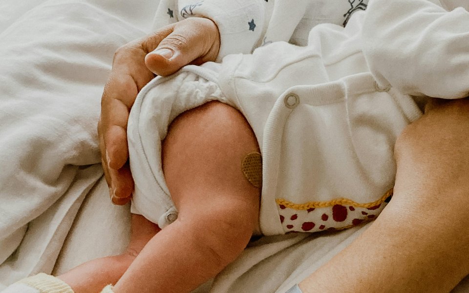 pasgeboren-baby-aan-de-borst.-enkel-beentje-en-beschermende-hand-moeder-te-zien