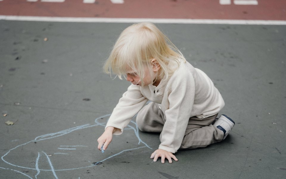 peuter-kleurt-op-speelplaats-met-stoepkrijt