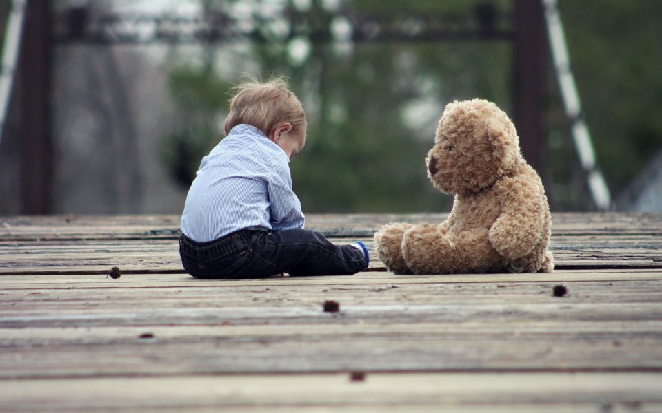 peuter en knuffelbeer zitten samen buiten
