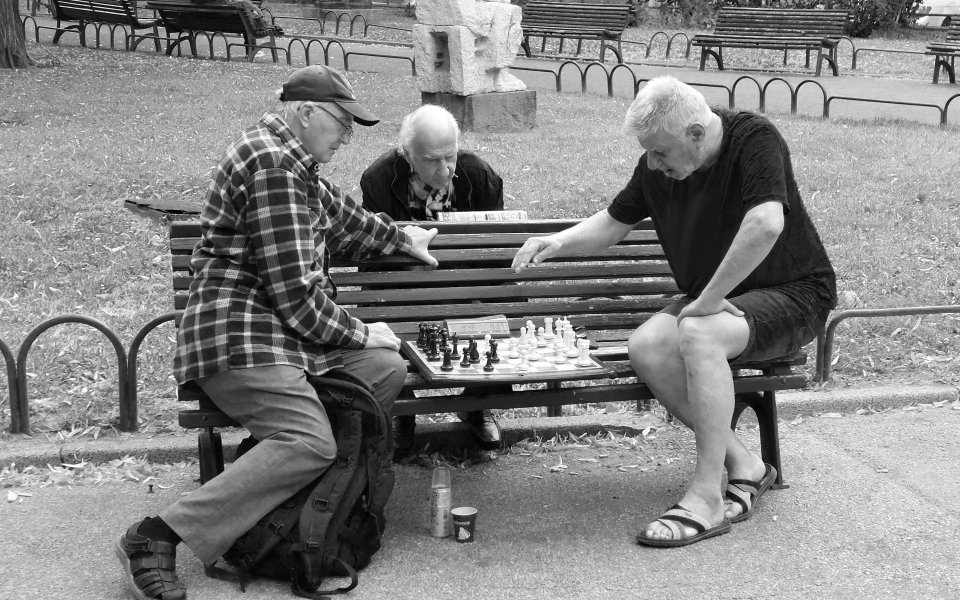 3 mannen die schaken op een parkbankje