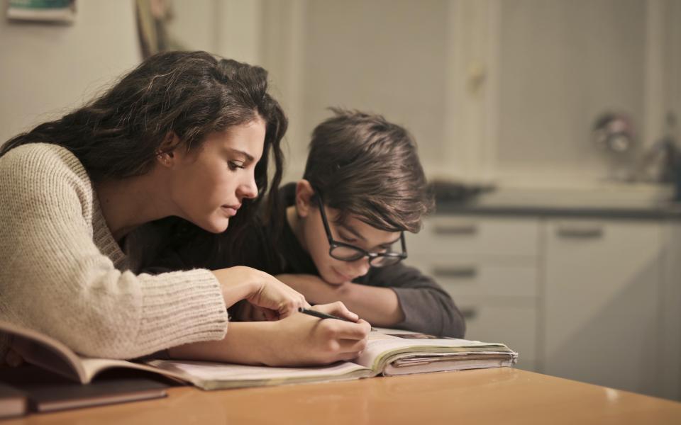 moeder helpt jongere bij huiswerk