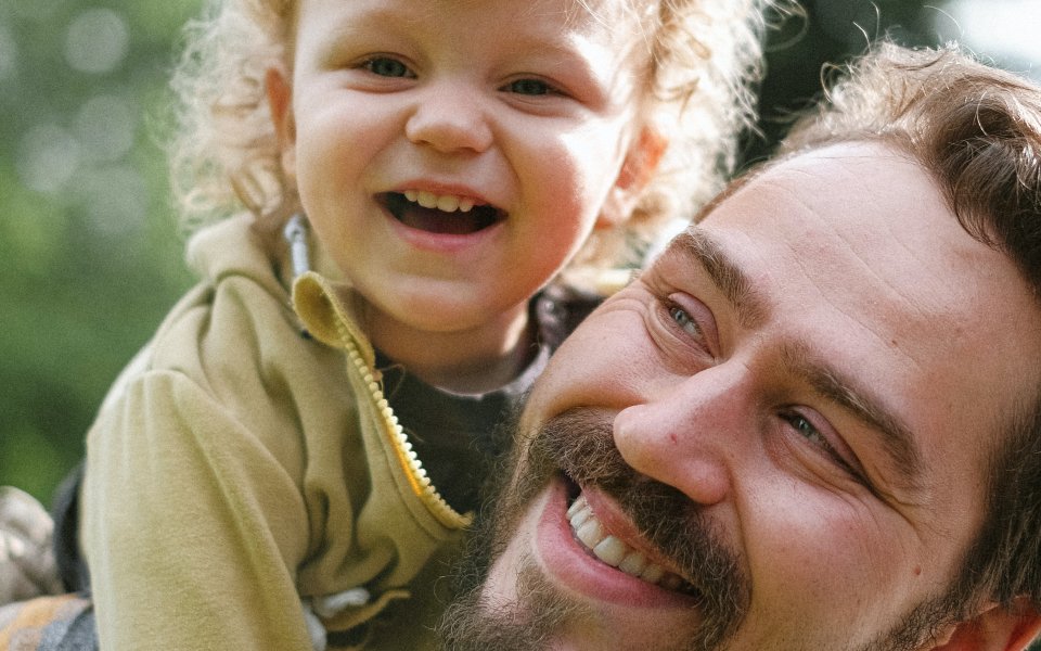 papa met peuter op rug, lachend