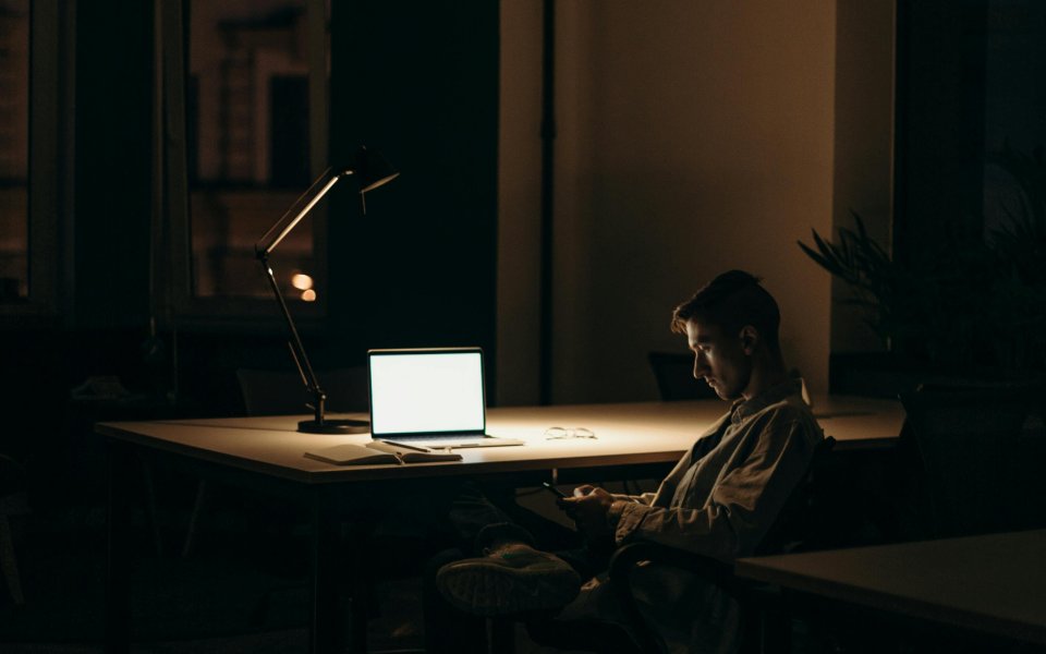 Jongeman zit in het donker naar een scherm te kijken