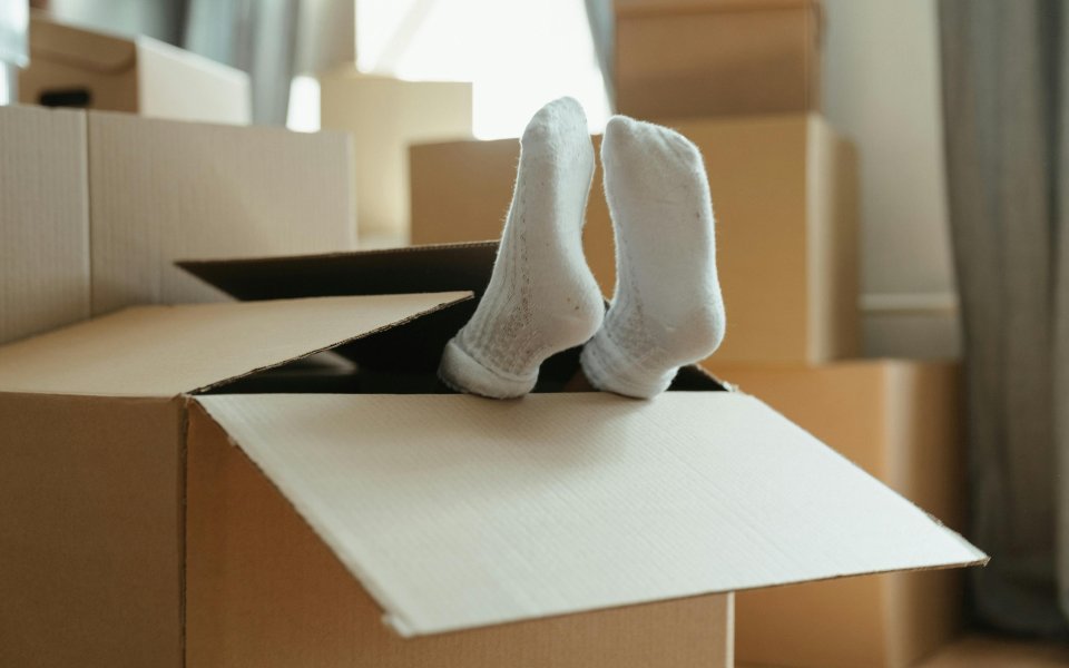 2 voeten steken uit een grote kartonnen verhuisdoos