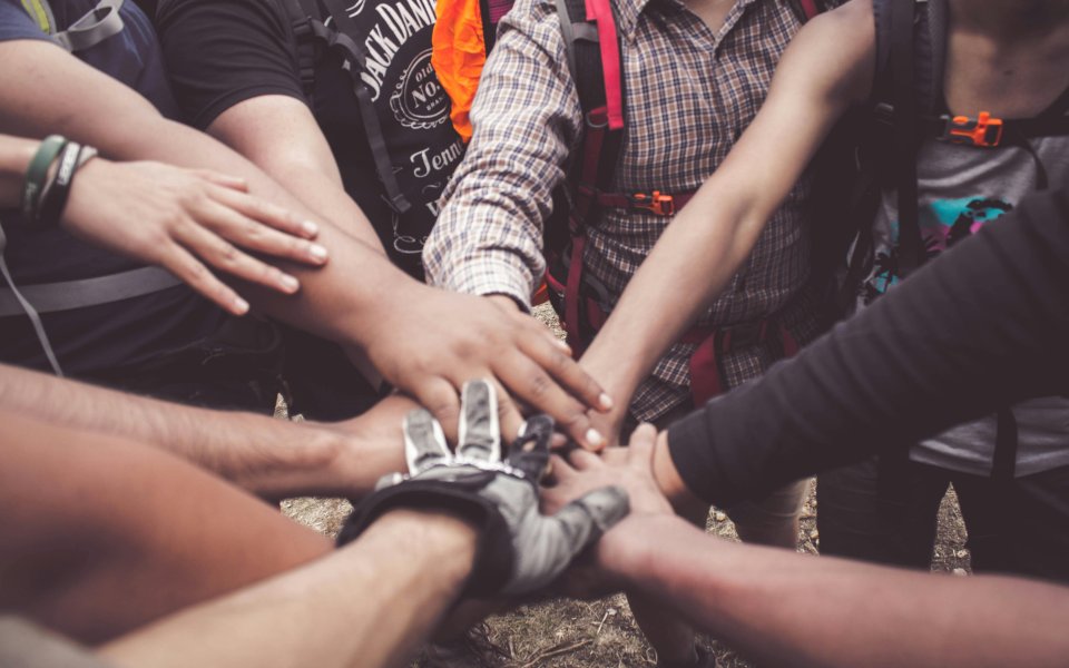 groep mensen die handen op elkaar legt in kring