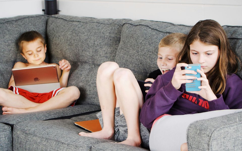 3 kinderen in de zetel, bezig op gsm of tablet