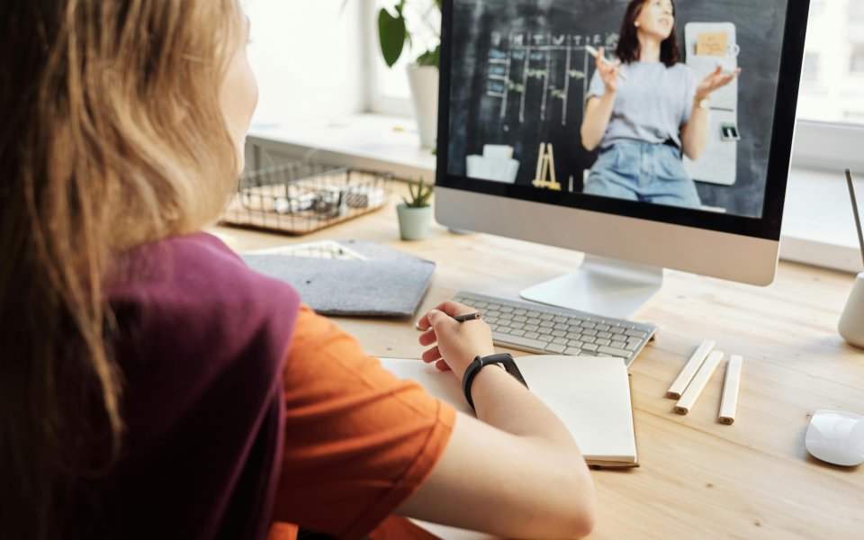 vrouw op rug kijkt naar vrouw die uitleg geeft op compterscherm