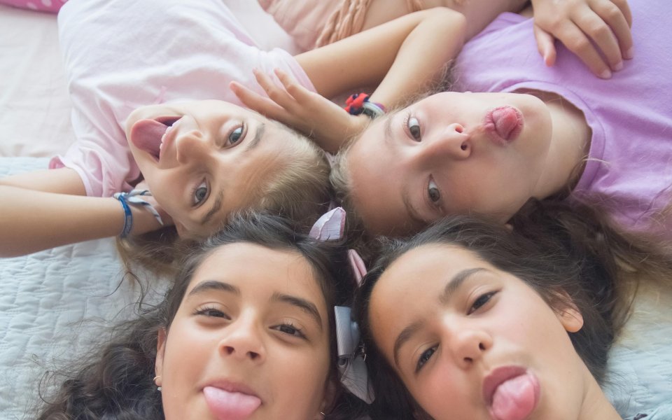 4 meisjes, liggend met hoofden bijeen, tong uitstekend