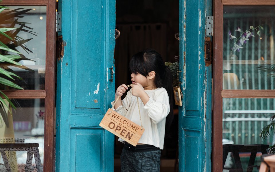 kind hangt bordje met open aan de deur