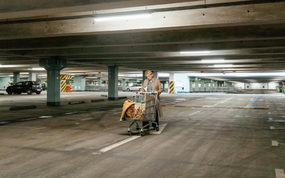 dakloze vrouw met winkelkar vol spullen in een parkeergarage