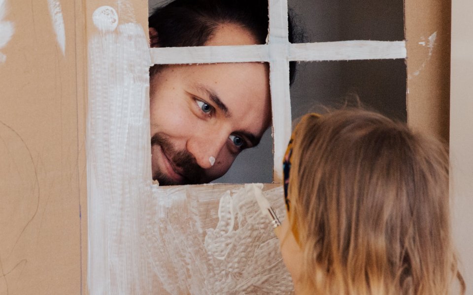 man kijkt door venster van geknutseld huis naar meisje