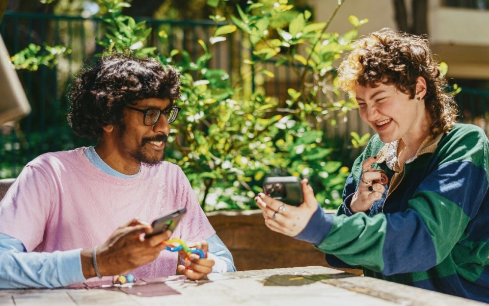 man van kleur en vrouw aan tafel met hun gsm