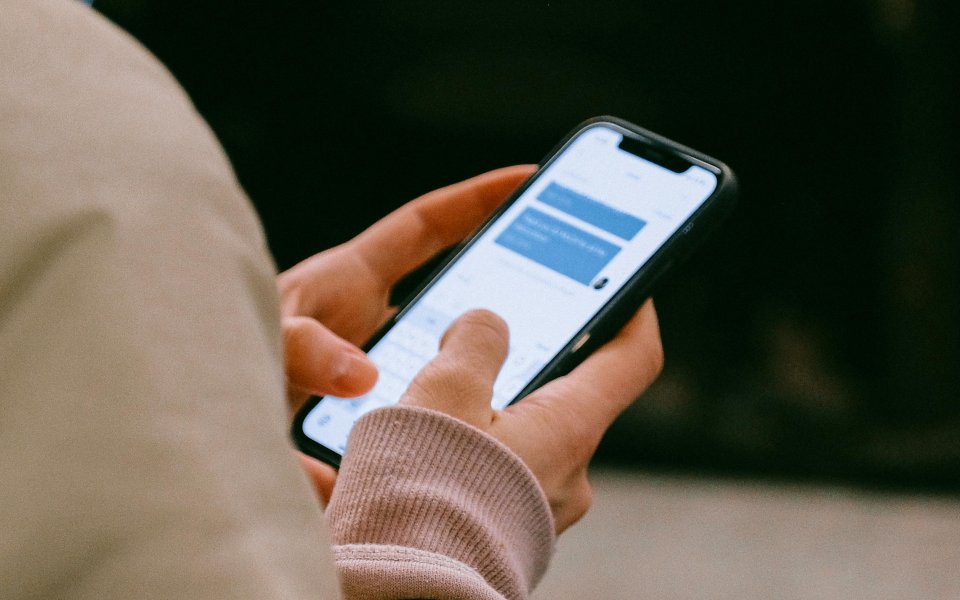 schouder met handen die een smartphone vasthouden