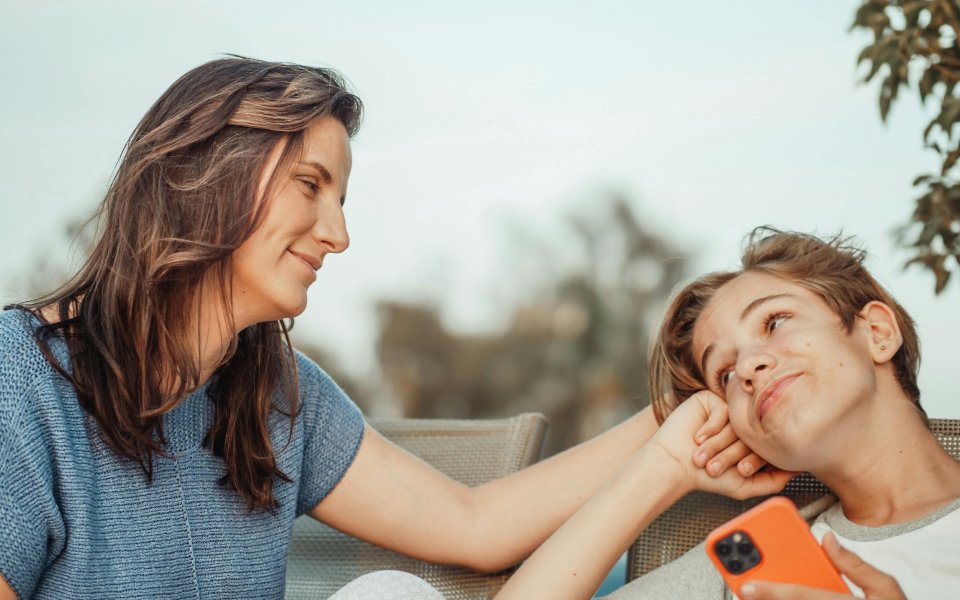 tiener-en-moeder-die-glimlachend-elkaar-aankijken