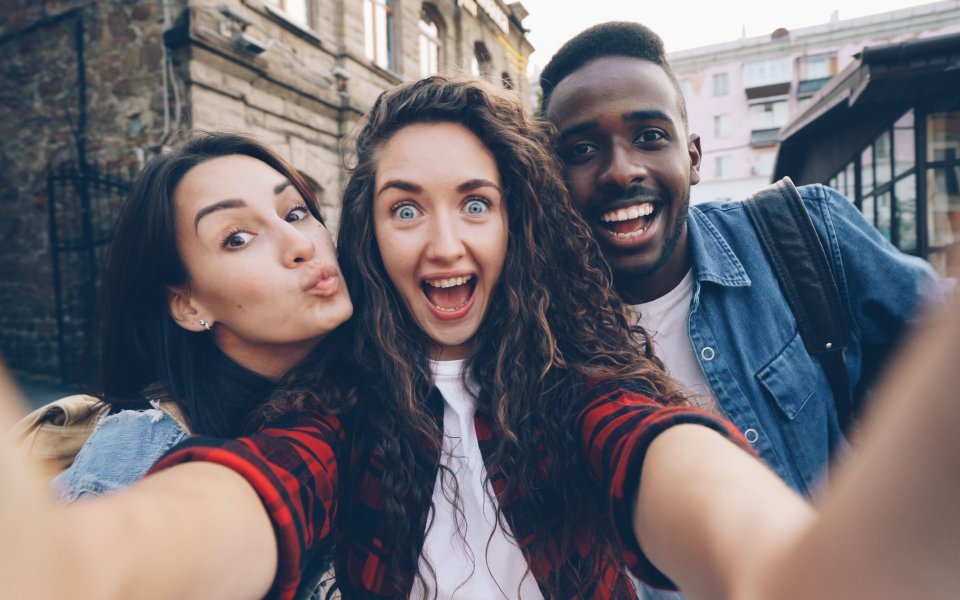 Twee jonge vrouwen en jonge man poseren voor selfie