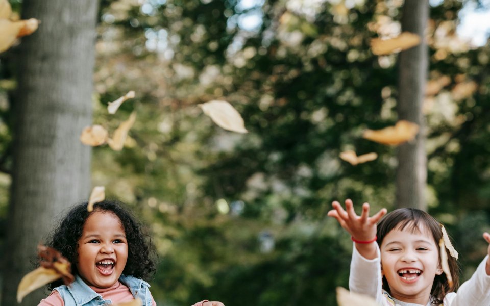 twee meisjes gooien met blaadjes in het bos