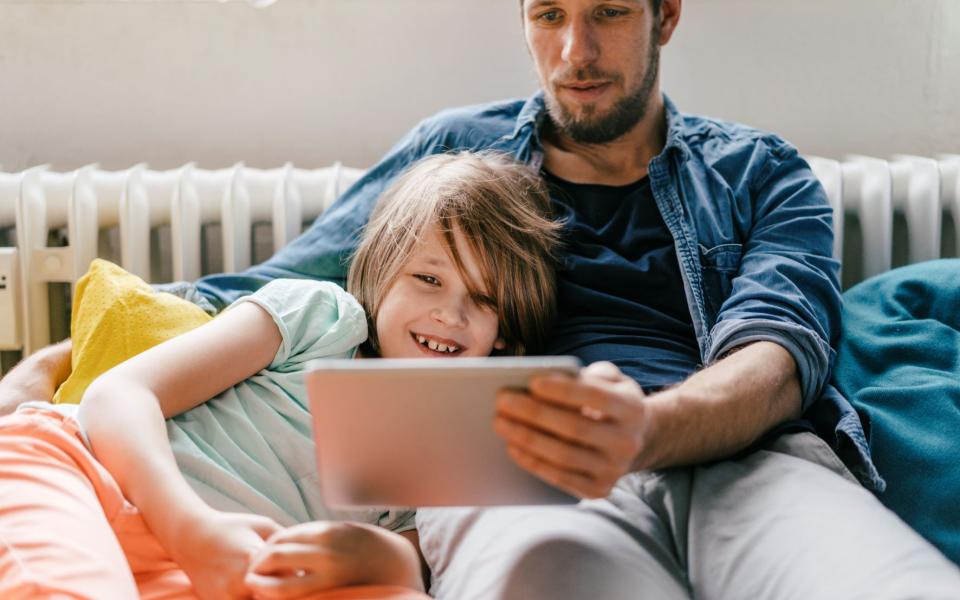 Kind en ouder kijken samen naar een tablet in de zetel