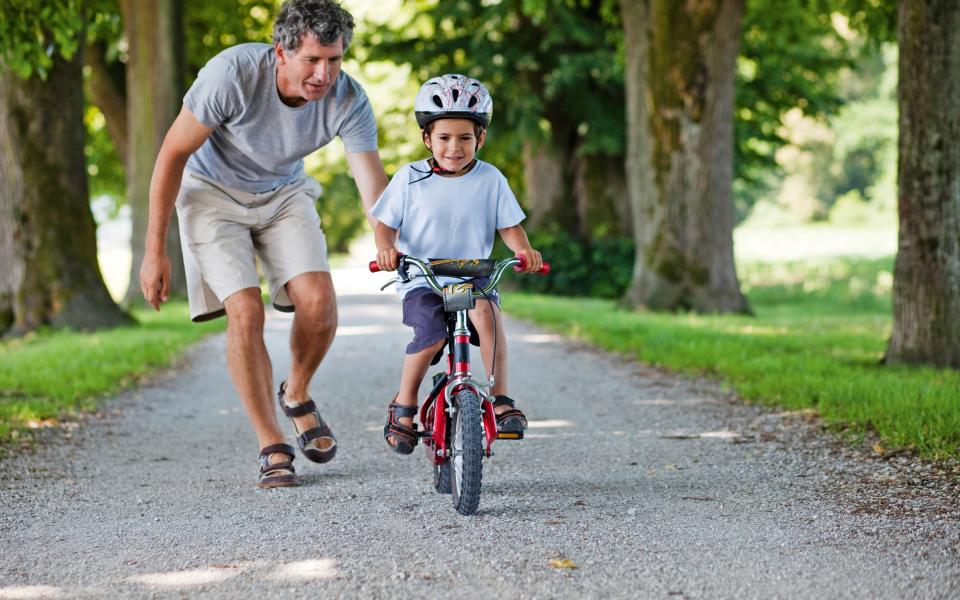 Vader helpt kind zelfstandig fietsen