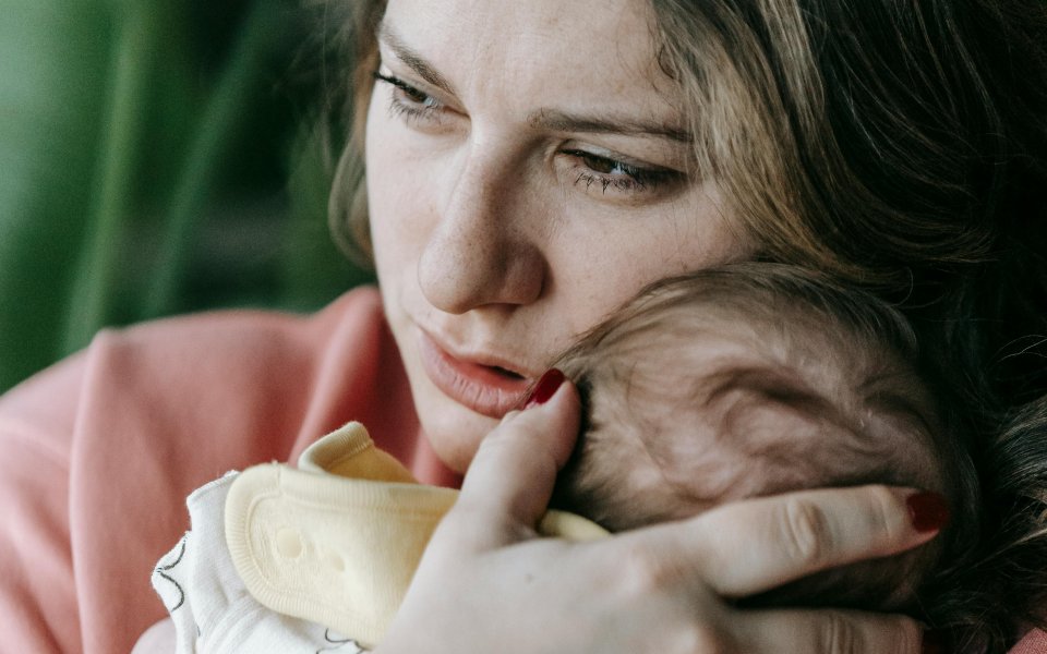 verontrust-kijkende-moeder-die-haar-babytje-dicht-tegen-zich-aan-drukt