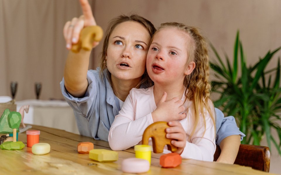 volwassene-wijst-iets-aan-aan-kind-met-down
