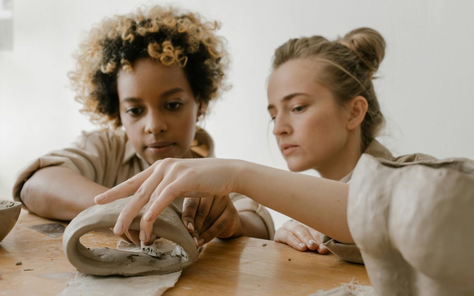 vrouw-kijkt-samen-met-jongere-naar-kleiwerkje