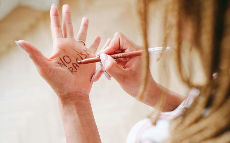 vrouw schrijf no racism op haar eigen hand