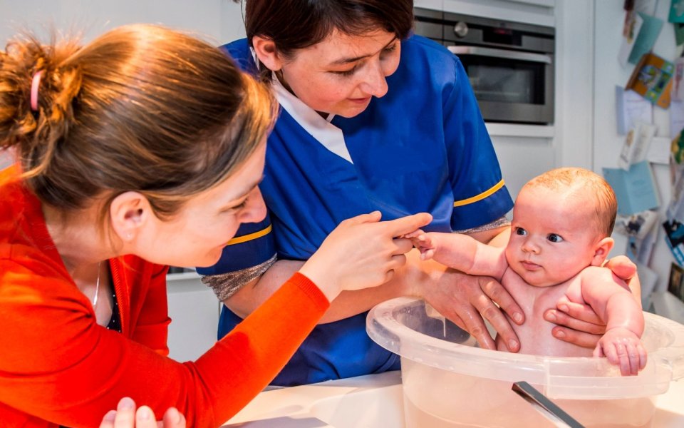 baby in emmerbad met mama en verpleegster