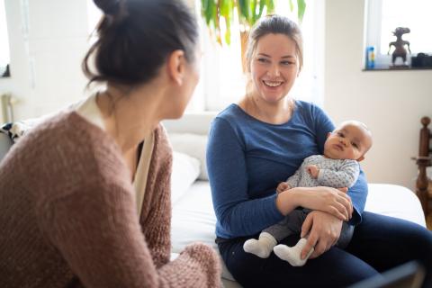 Gesprek tussen een verpleegkundige en mama met baby op schoot