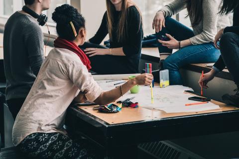 Collega's zitten samen aan tafel rond uitgetekende plannen