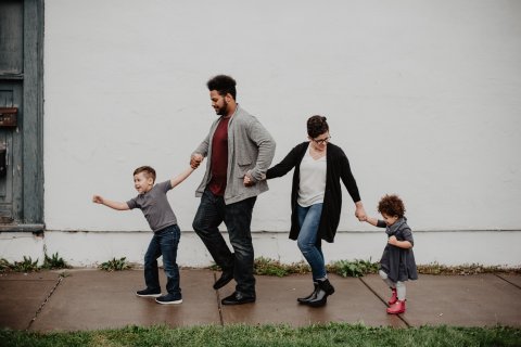 Multiculturele familie dat hand in hand over straat wandelt