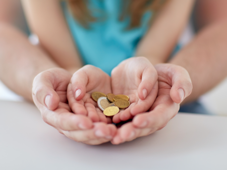 kinderhand met centjes omsloten door volwassen hand
