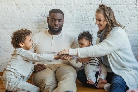 multicultureel gezin met 2 kleine kinderen dat handen op elkaar legt