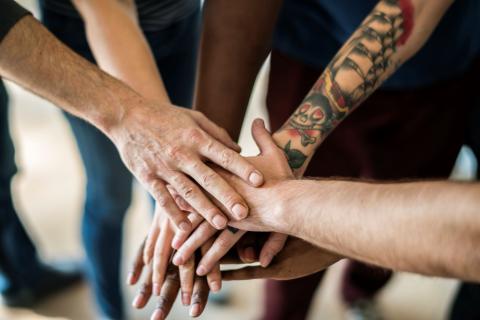 Stapel handen op elkaar, teken van samenwerking onder diverse partners