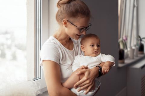 Jonge moeder draagt baby op haar arm en lacht