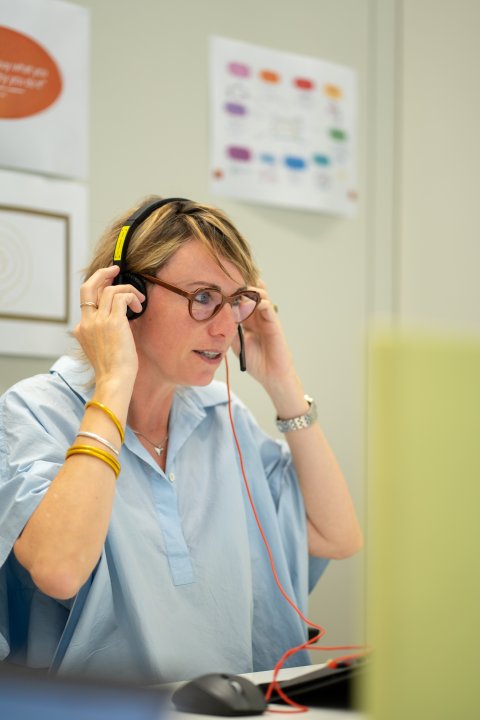 Julie aan haar bureau met koptelefoon op