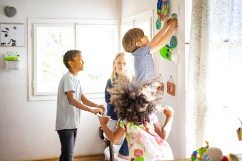 kinderen hangen kunstwerkjes op aan de muur