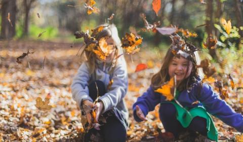 Twee kinderen spelen buiten in het bos met bladeren tijdens de herfst