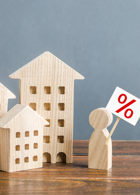 Houten huisjes met een houten figuurtje dat een percentageteken vasthoudt